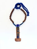  A quiet sculptural presence. One-of-a-kind sculptural necklace built around an  architectural bookmark wooden pendant — vertical, solid, grounded. Various stones, golden coral, a Venetian (Murano)chevron trade glass bead, wood beads on Cobalt blue adjustable braided threads complete this unique piece handmade in Lebanon with materials sourced all over the world. 
An Architectural and tactile totem. 