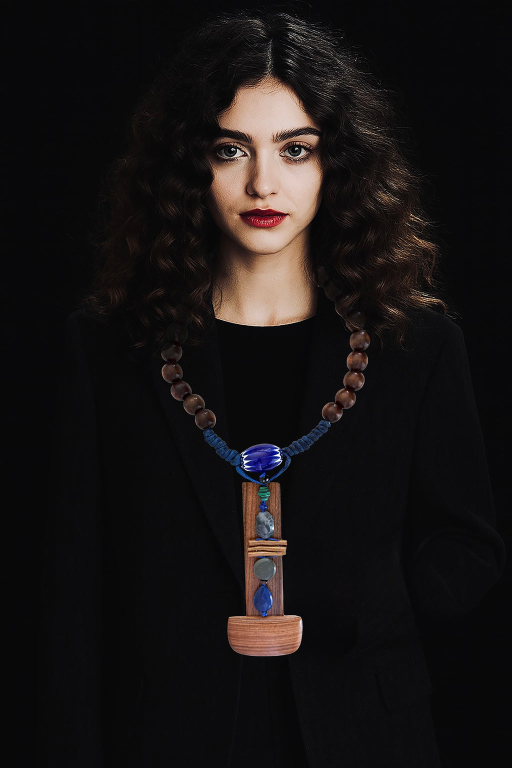  A quiet sculptural presence. One-of-a-kind sculptural necklace built around an  architectural bookmark wooden pendant — vertical, solid, grounded. Various stones, golden coral, a Venetian (Murano)chevron trade glass bead, wood beads on Cobalt blue adjustable braided threads complete this unique piece handmade in Lebanon with materials sourced all over the world. 
An Architectural and tactile totem. 