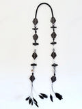 Ritualistic. Tribal Modern aesthetic. Unique piece long open drop necklace, handmadein Lebanon with materials sourced worldwide.Black geometric shapes, pearls,onyx,black coral, druzy quartz and feather tassels.Raw materials. Double feather pendants. Sophisticated, collectible, wearable artifact.