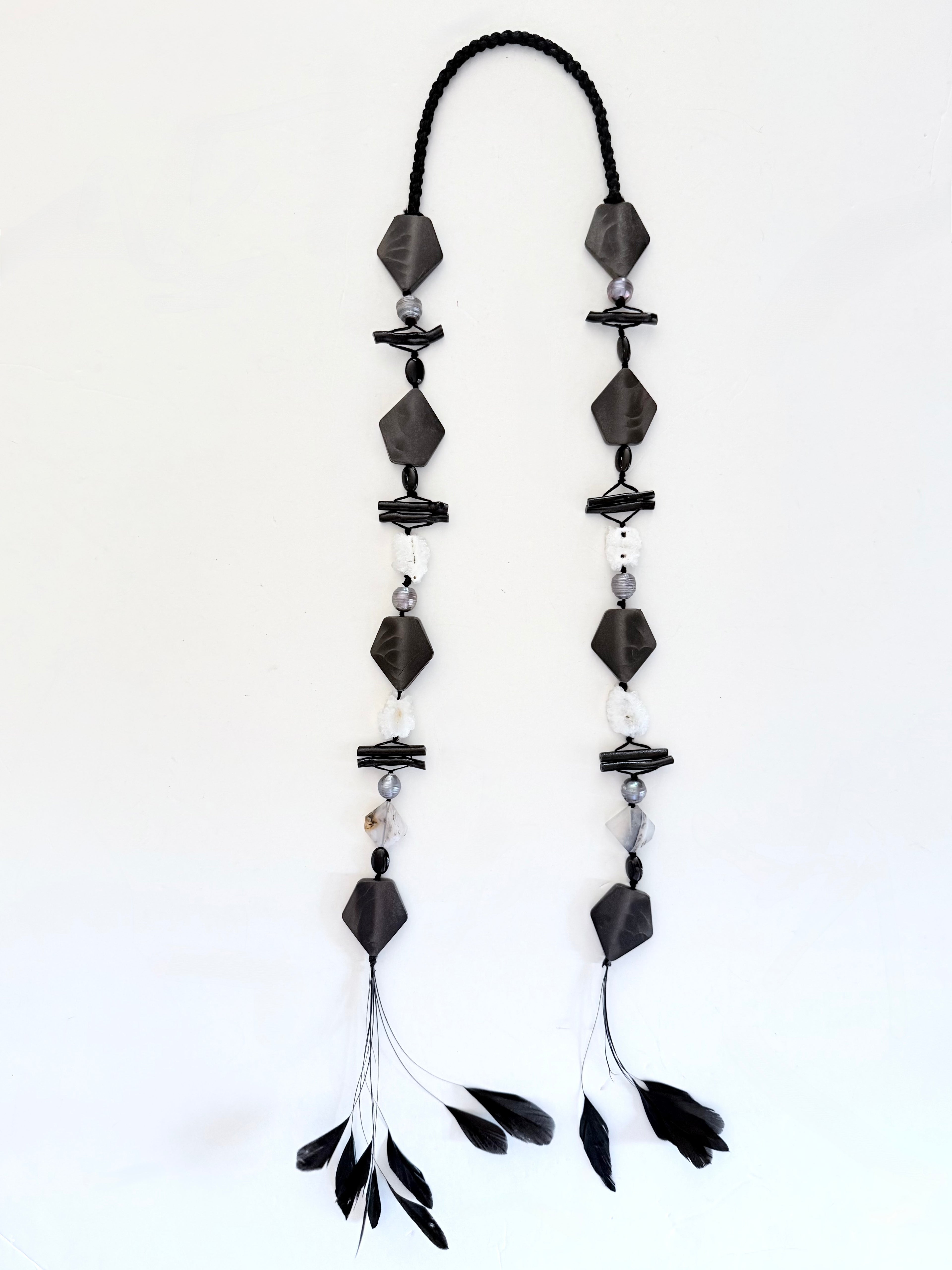 Ritualistic. Tribal Modern aesthetic. Unique piece long open drop necklace, handmadein Lebanon with materials sourced worldwide.Black geometric shapes, pearls,onyx,black coral, druzy quartz and feather tassels.Raw materials. Double feather pendants. Sophisticated, collectible, wearable artifact.