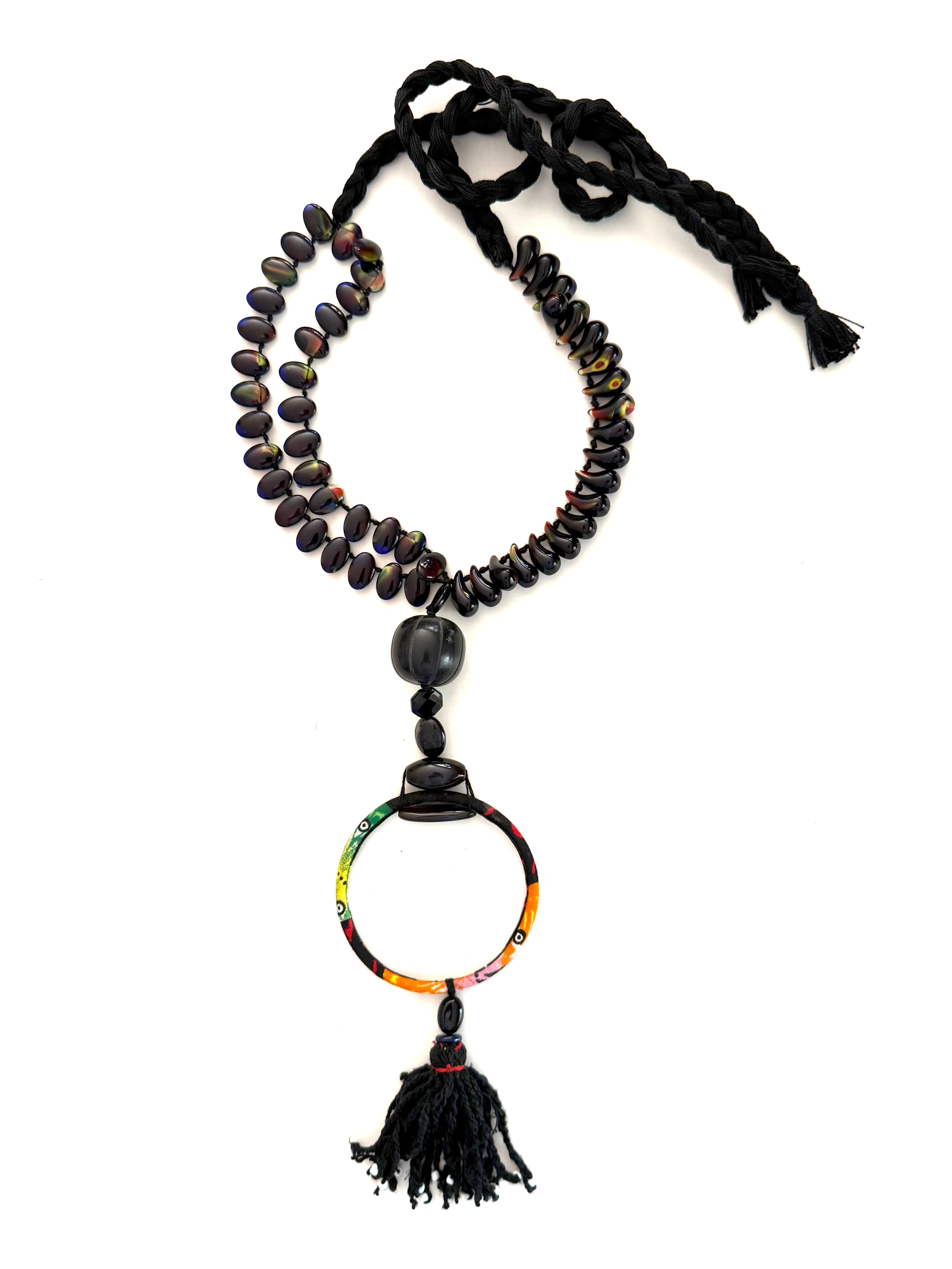 Black adjustable cotton braided threads with a double strand of lampwork magatama and oval shaped beads. Onyx stones, carved horn, an African wax fabric bracelet Finished with an antique Ottoman tassel.