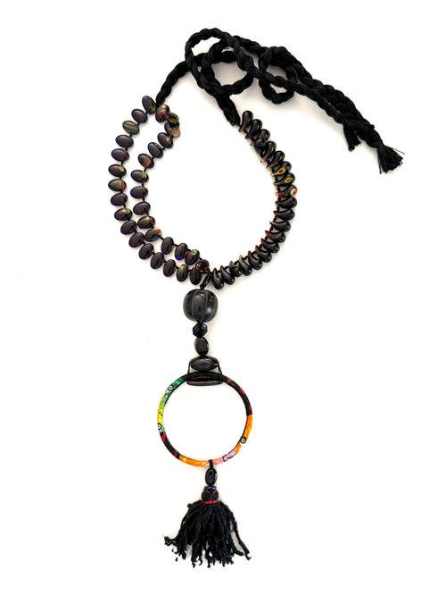Black adjustable cotton braided threads with a double strand of lampwork magatama and oval shaped beads. Onyx stones, carved horn, an African wax fabric bracelet Finished with an antique Ottoman tassel.