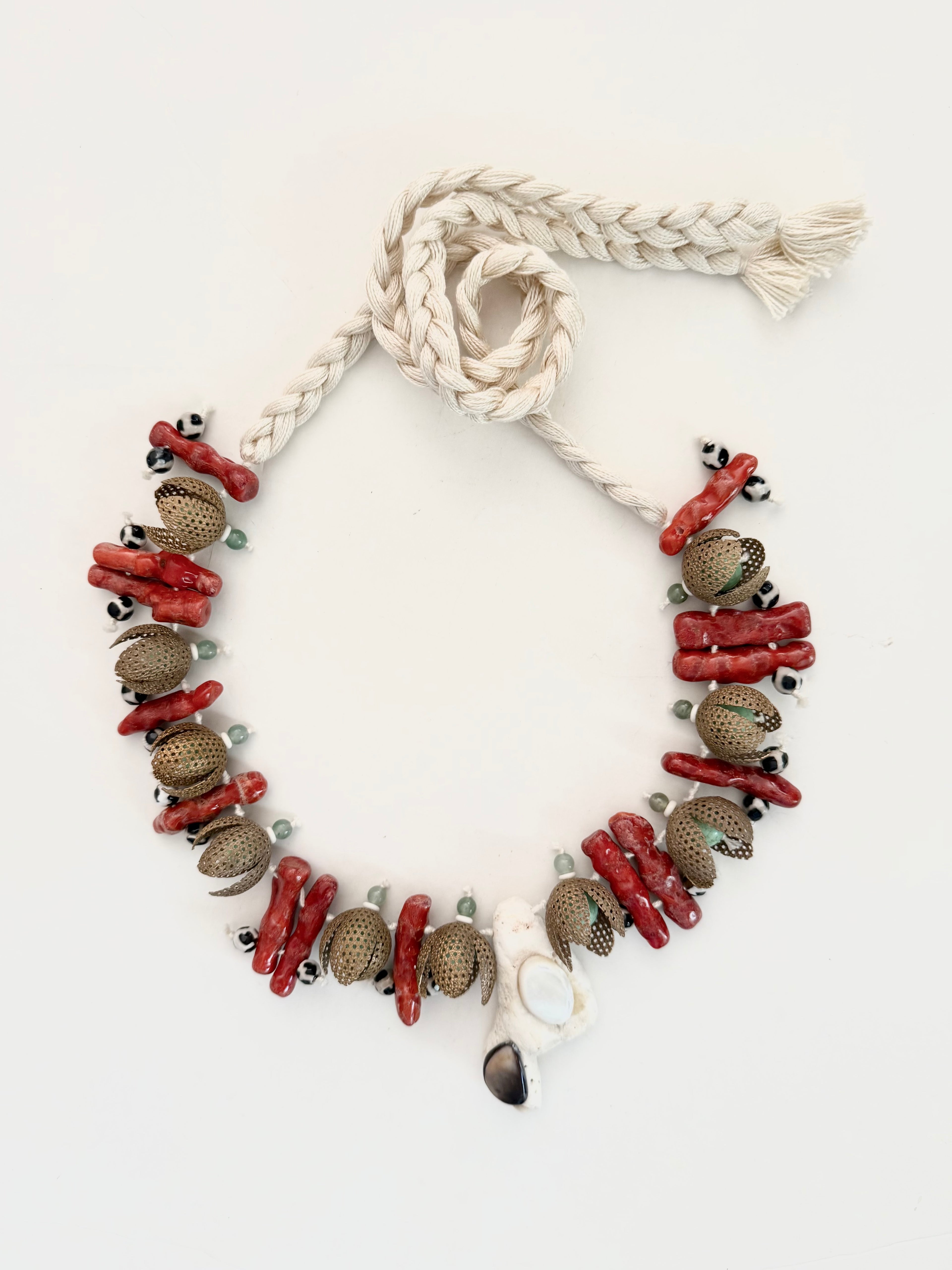 Fragments of the Sea ... from Mediterranean travels and curated finds. One-of-a-kind handcrafted necklace assembling coral branches, oxidized metal, semi-precious stones, and a pumice centerpiece set with mother of pearl. Adjustable braided cotton threads holds together this timeless piece handmade in Lebanon with worldwide sourced materials. Objects that outlive trends.