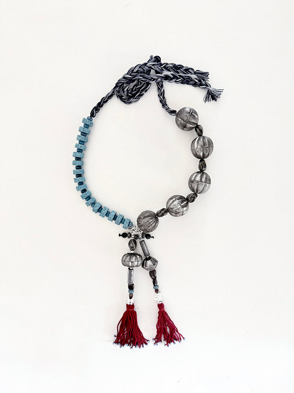 Pièce unique — handmade in Lebanon with adjustable braided cotton threads, metal, ceramics, lava beads and aquamarine stones. Finished with deep Ottoman crimson tassels.

Raw elements. Refined construction.