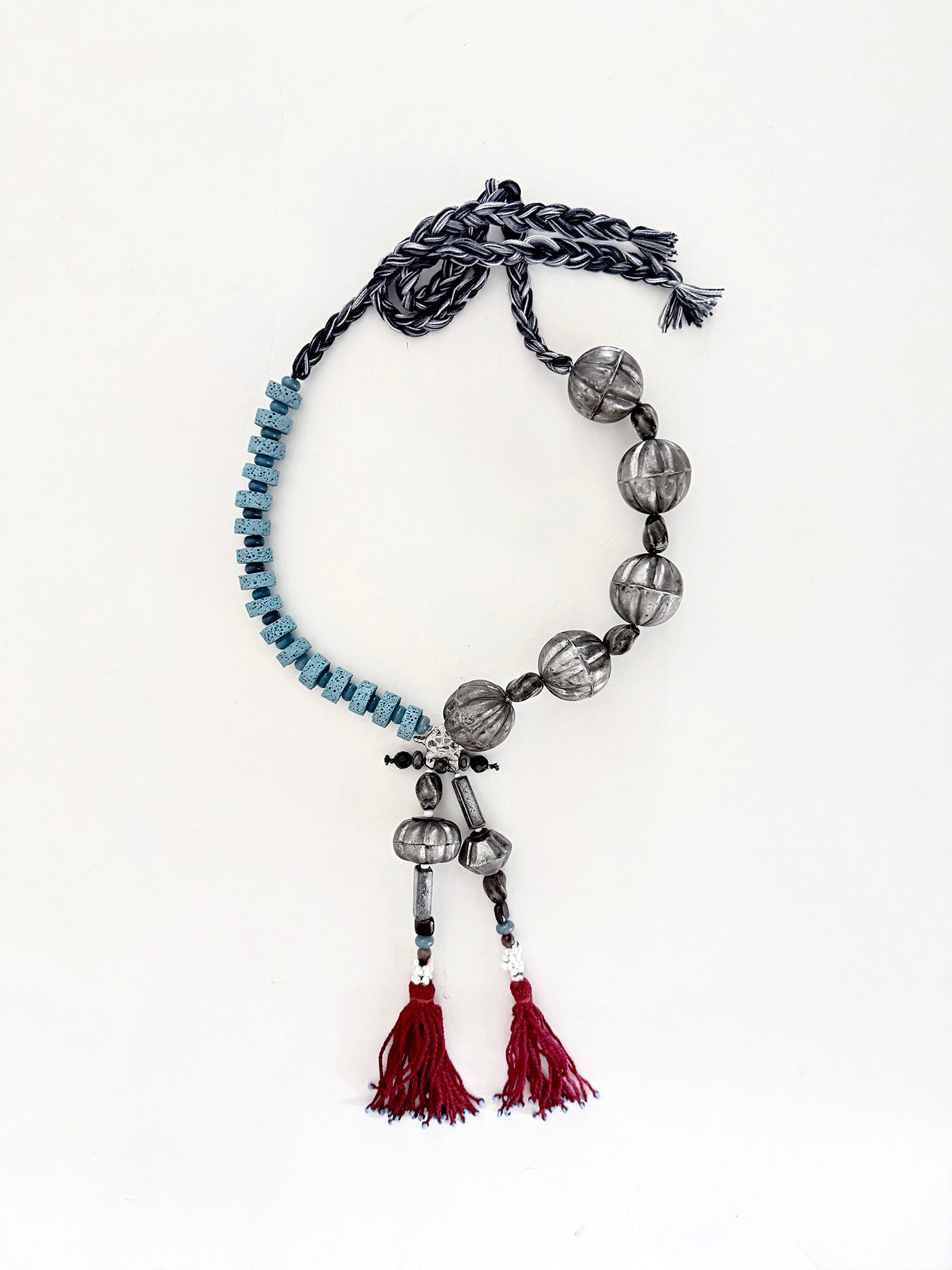 Pièce unique — handmade in Lebanon with adjustable braided cotton threads, metal, ceramics, lava beads and aquamarine stones. Finished with deep Ottoman crimson tassels.

Raw elements. Refined construction.