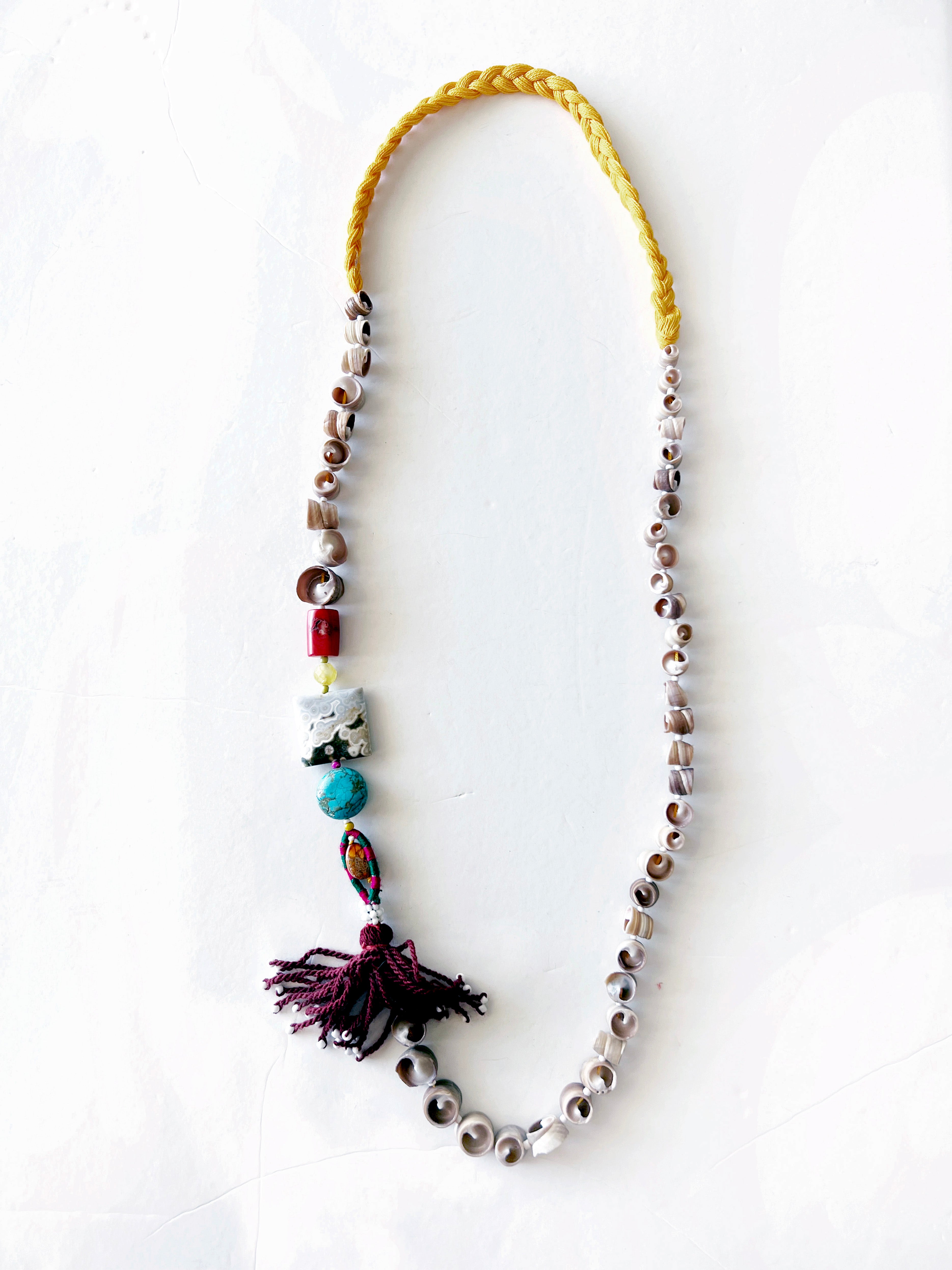 A gathering of sea, thread and time.
Pièce unique handmade in Lebanon with braided yellow cotton threads, natural shells, coral, ocean jasper and turquoise stones and an antique Ottoman tassel.
A wearable relic for sea nomads.